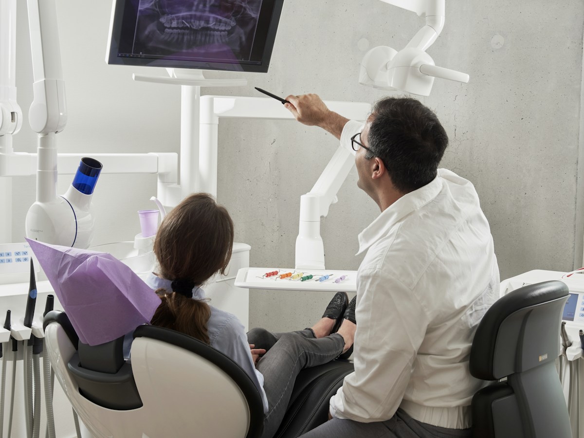 Illustrative photo of a dentist explaining care to a patient; not clinic staff